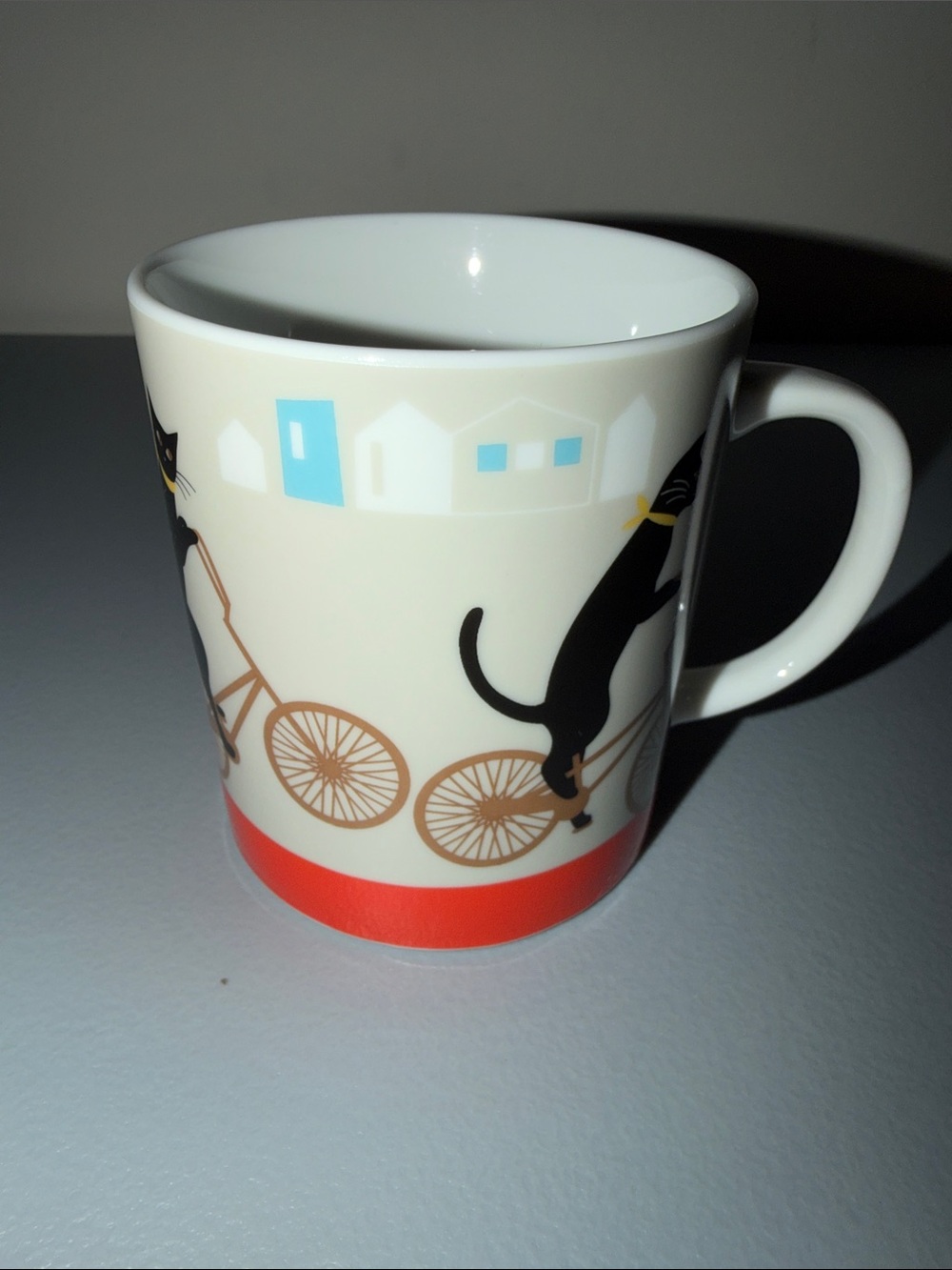 Cream Porcelain Mug with Black Cat Bicycle Design and Red Accent